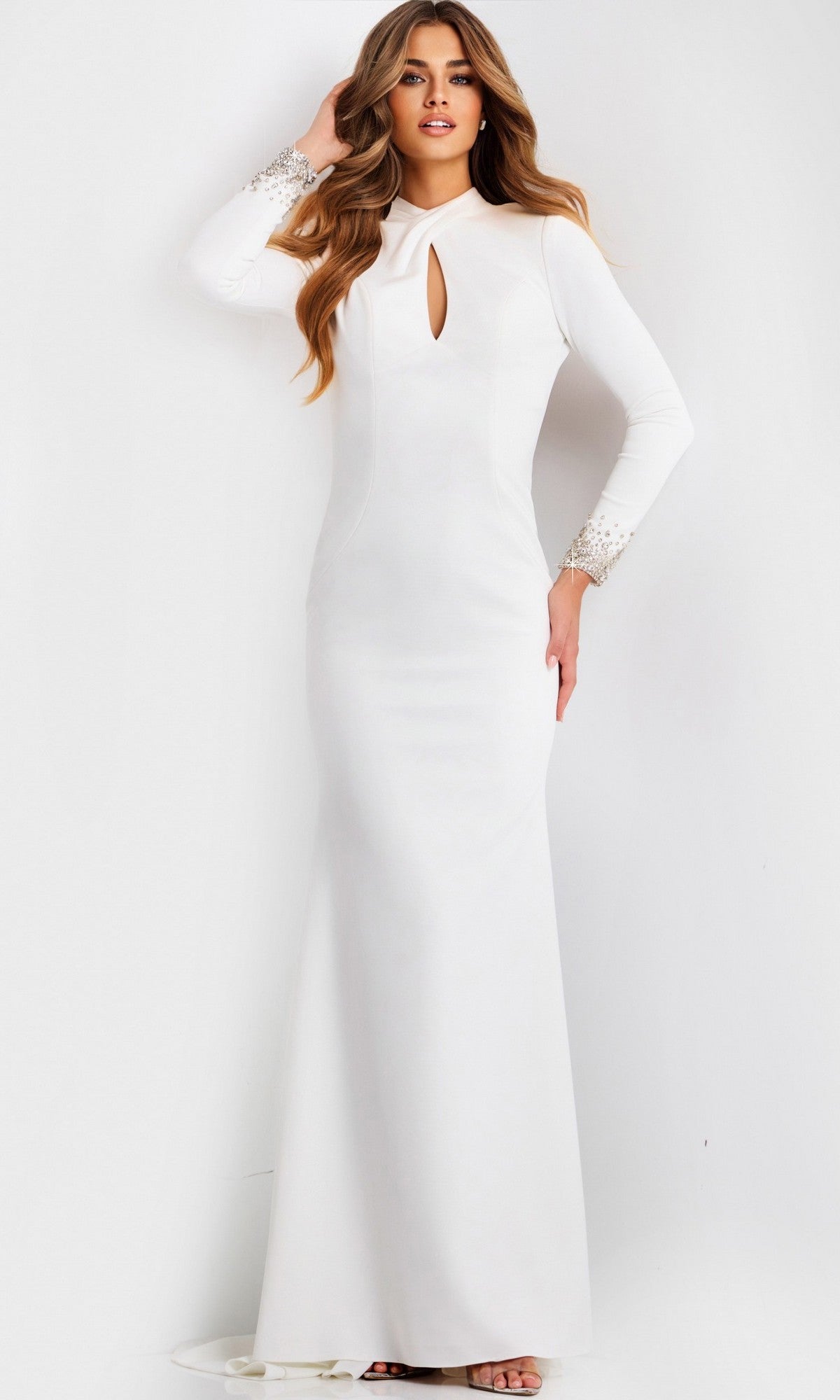 A woman wears the Jovani 49126 Long Prom Dress in off white—a floor-length crepe gown with long sleeves, a front keyhole detail, and embellished cuffs—standing against a plain light background.